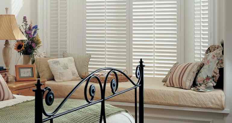 White shutters in a chic bedroom bay window.